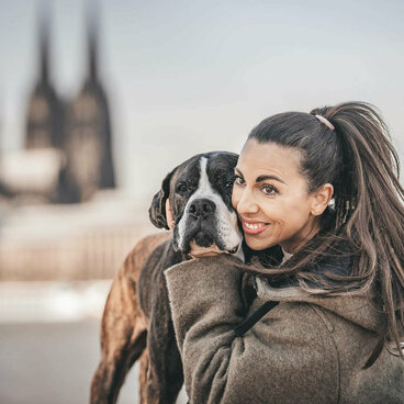 Frau umarmt Hund am Rhein