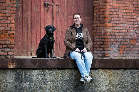 Frau sitzt mit einem Hund auf der Mauer